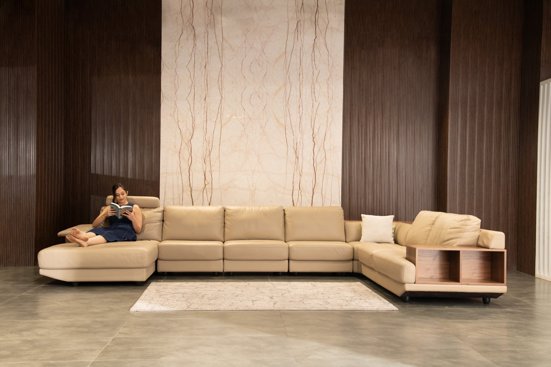 Beige sectional sofa in a modern living room with a person reading a book.slider_item_N9pTb8