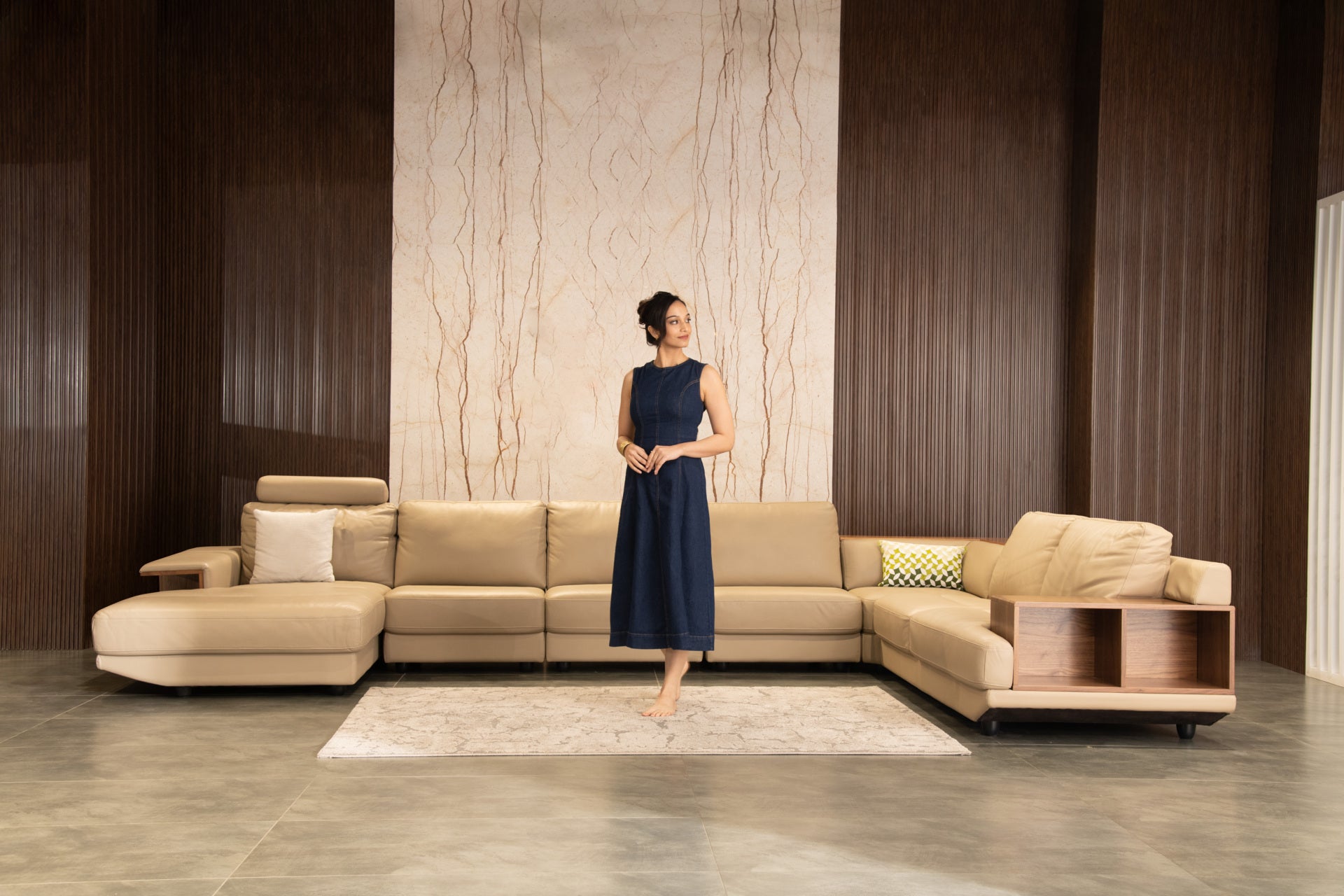 Woman standing in a modern living room with a beige sectional sofa.slider_item_GjB3Hq